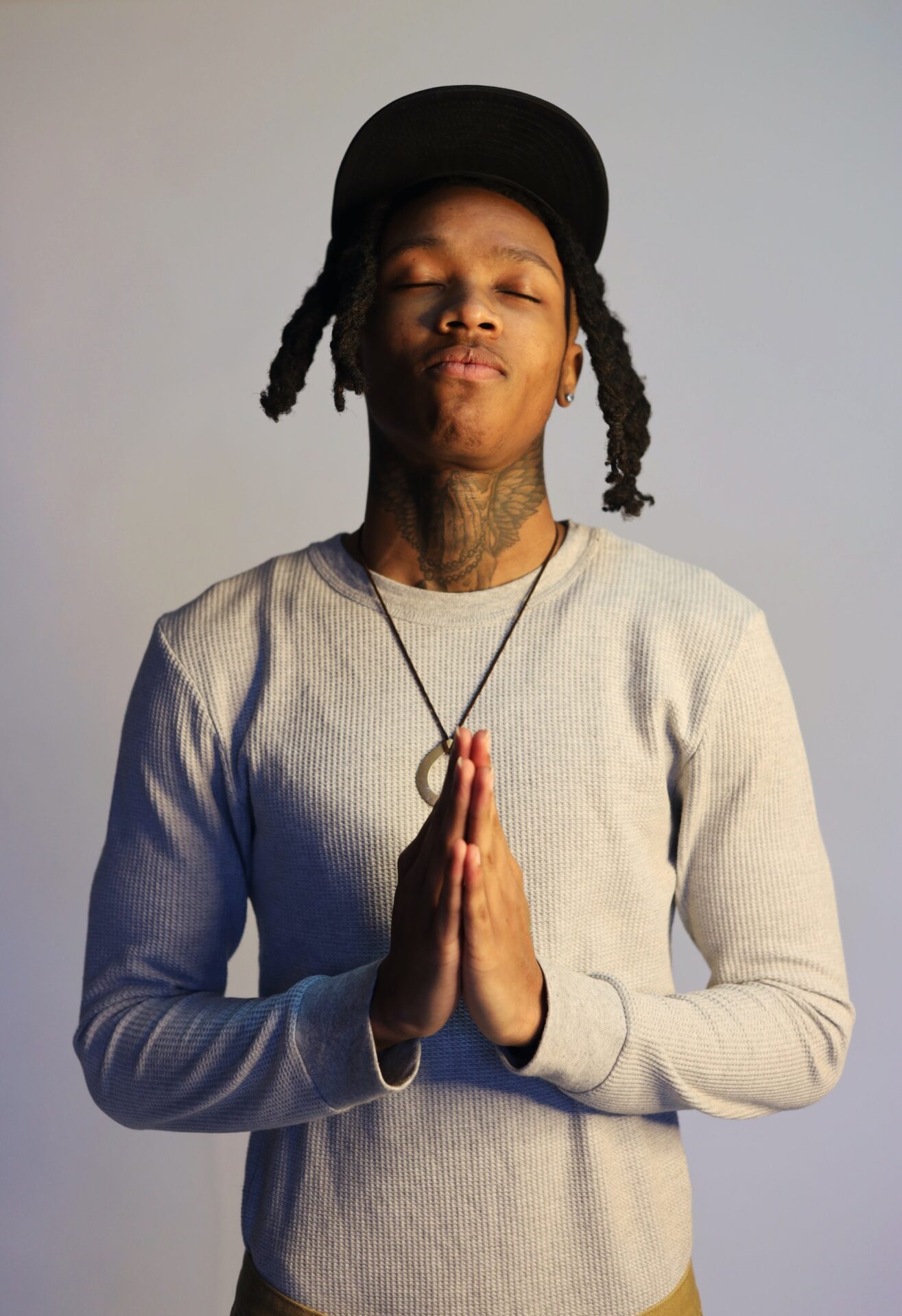 Young Man Putting His Hands Together to Pray and Standing with Eyes Closed
