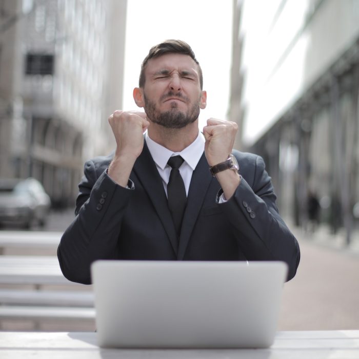 Man in Black Suit Sitting on Chair Beside Buildings