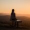 woman sitting on bench over viewing mountain
