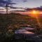 cross in an open field by the setting of sun