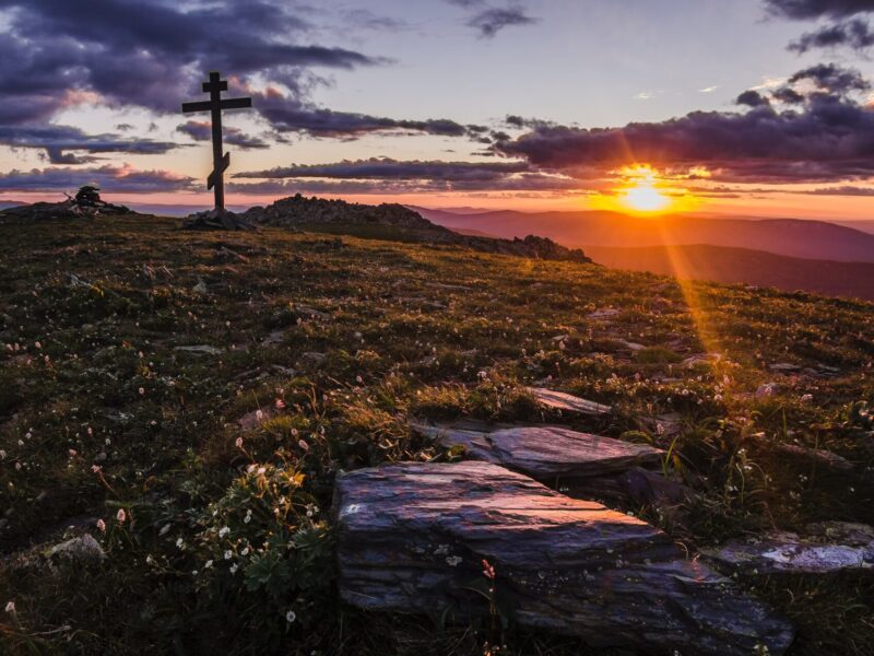 cross in an open field by the setting of sun