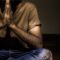 man wearing beige crew-neck shirt and blue faded jeans meditating